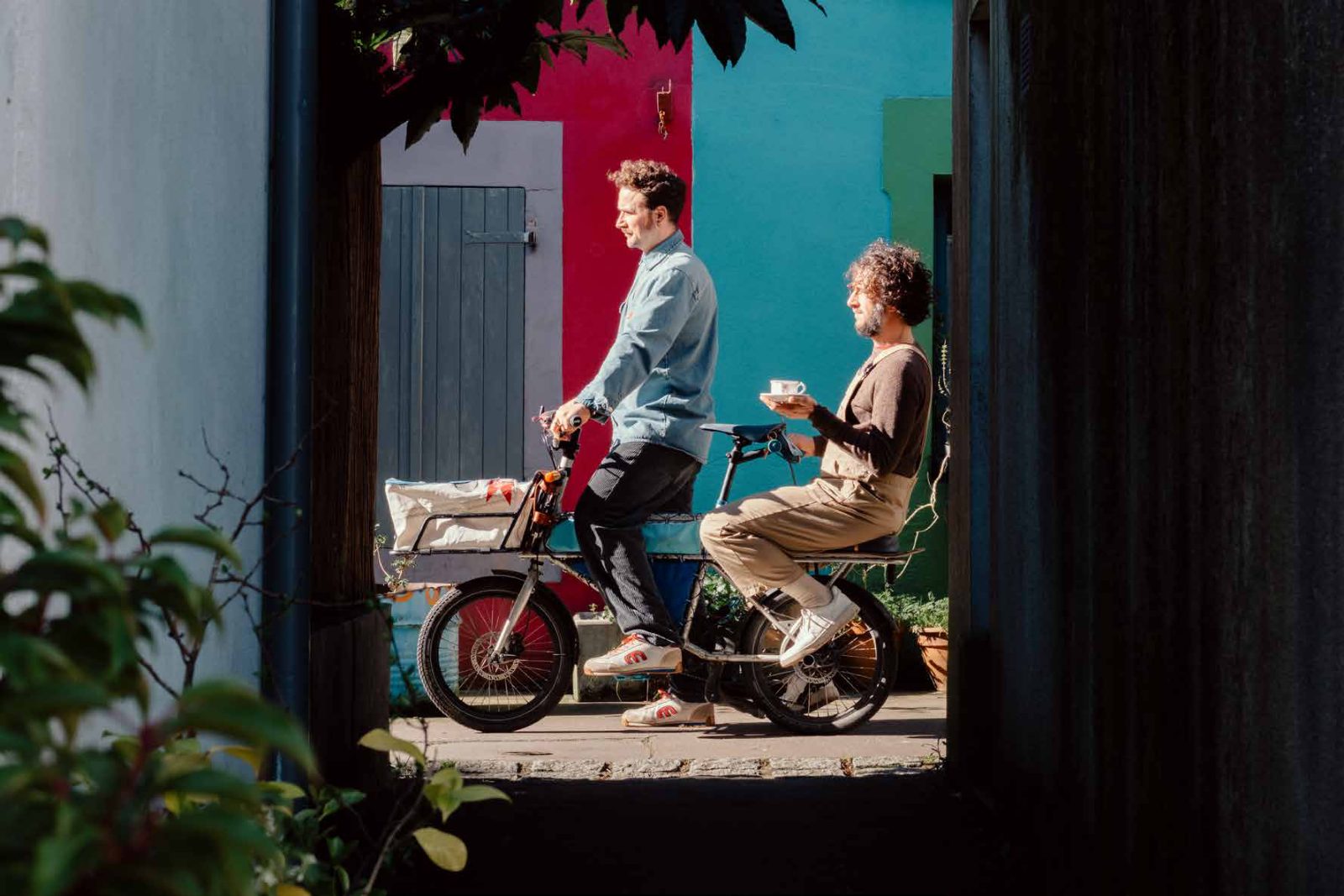 Deux personnes sur un vélo cargo, café à la main